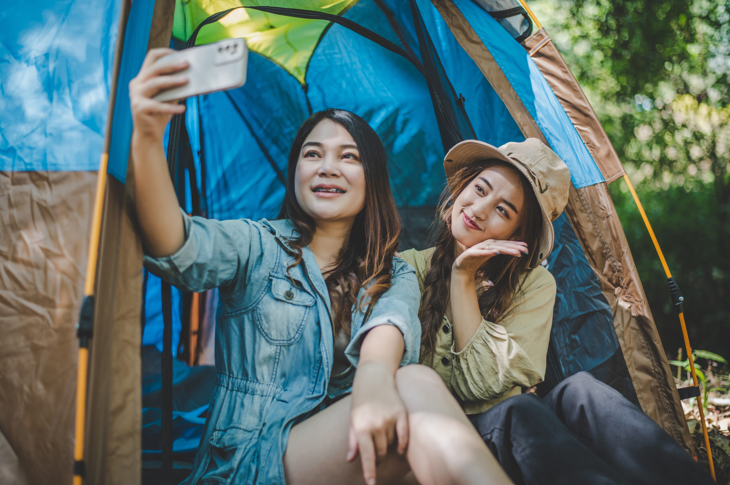 Asian pretty woman and friend use smartphone selfie on camping