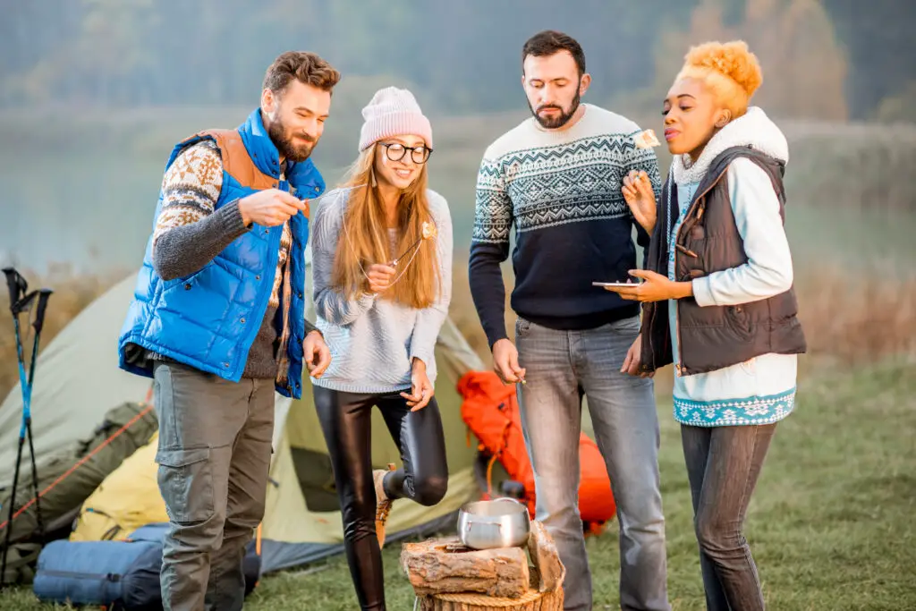 Friends in sweaters eating fondue outdoors